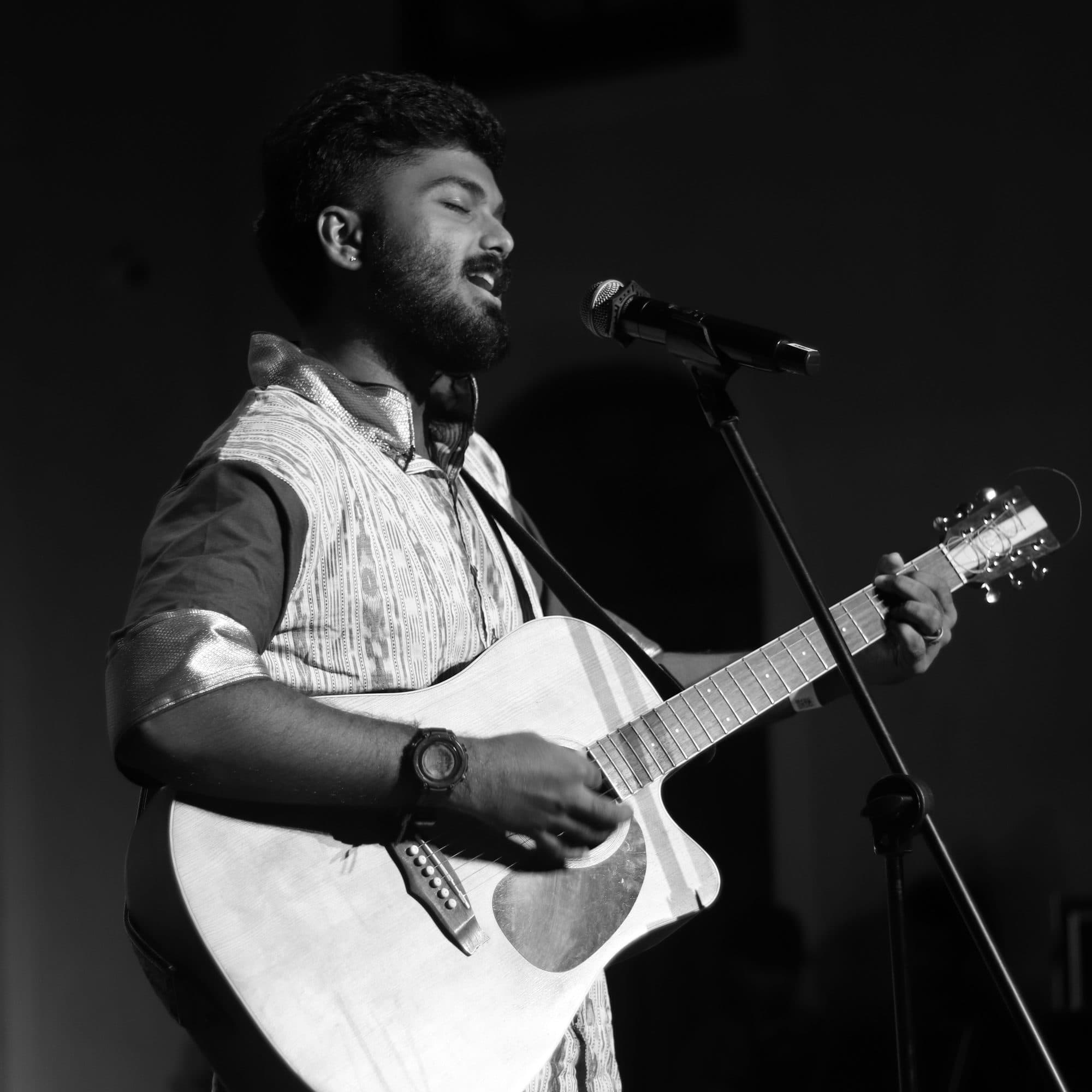 Ajay Nathan at the microphone, black and white